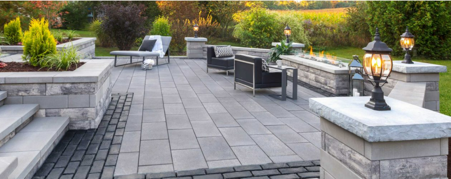 Modern paver patio featuring built-in seating, a fire feature, and outdoor lounge furniture set against a landscaped backdrop.